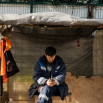 Строитель отдыхает с мобильным устройством на строительной площадке