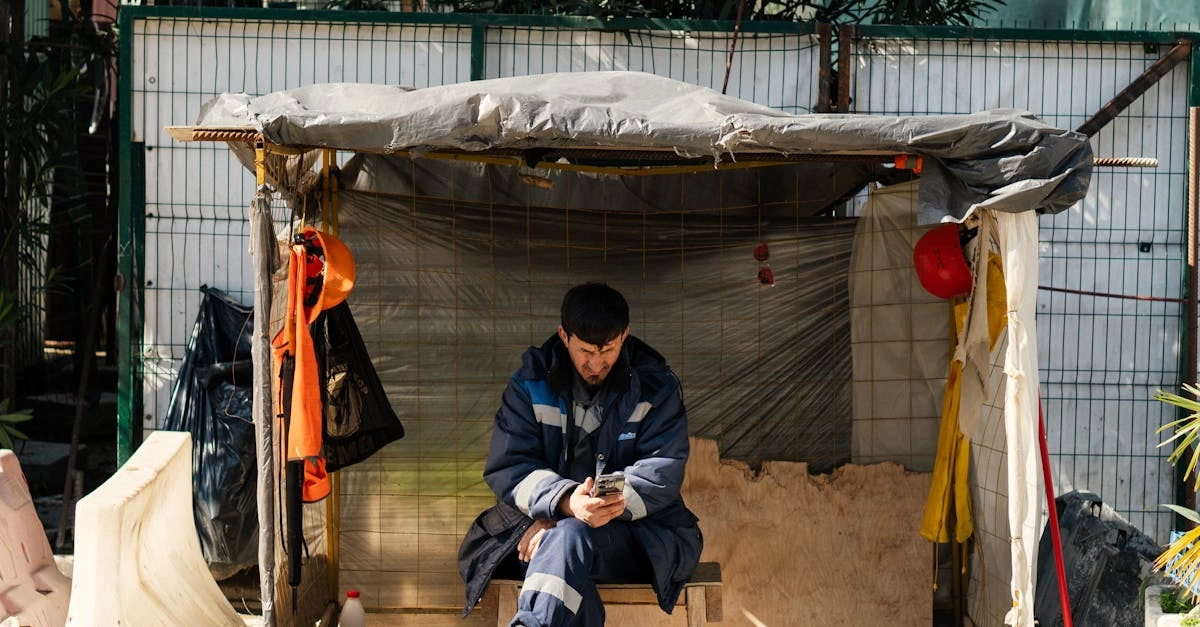 Строитель отдыхает с мобильным устройством на строительной площадке